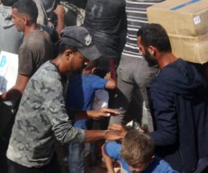Palestinians crowd onto aid trucks moving through Gaza