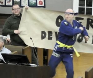 Cranford candidate Will Thilly kung fu kicks through protest signs
